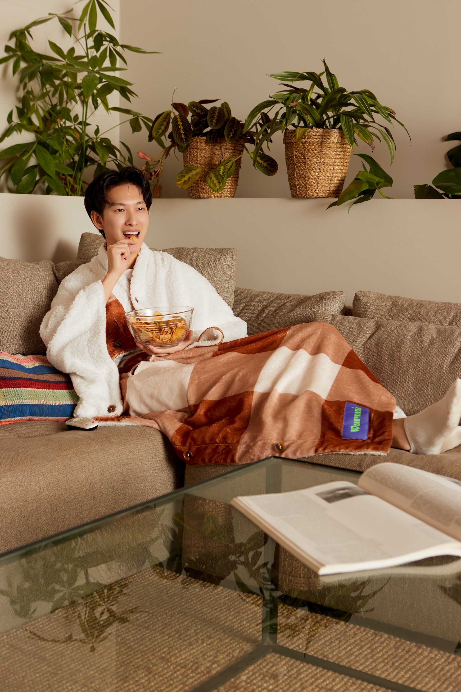 Warmzie wearable blanket folded - hoodie blanket- heated blanket- flannel - sherpa - brown beige - model on couch - watching tv - netflix